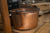 Side profile of the antique copper kettle showing its hammered texture and blacksmithed handle.