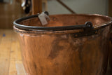Forged iron rim and handle detail on an antique hand-hammered copper kettle.