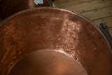 Close-up of the warm, hammered copper texture inside the antique kettle.