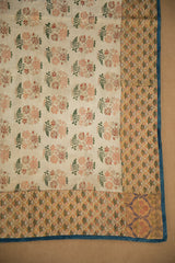 Corner of antique Persian brocade textile, showing delicate florals, finely patterned border, and blue edge.