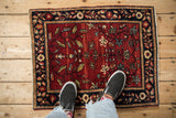 Antique Farahan Sarouk rug mat shown for scale, with an abrashed red field and floral motifs.