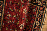 Antique Farahan Sarouk rug detail showing the abrashed red pile with starburst florals and serrated leaves.