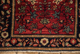 Detail of the navy blue floral border and short fringe on an antique Persian Farahan Sarouk rug.