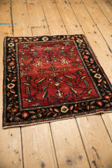 Angled view of an antique Farahan Sarouk rug highlighting its abrashed red field and dark floral border.