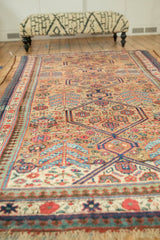 Angled perspective of a collector's antique Serab carpet, showing gem-toned medallions on a camel wool field.