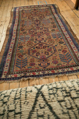 An antique nomadic Serab carpet laid out, displaying the full length of its interconnected medallions.