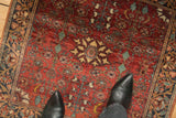 Time-softened wool pile of a vintage Persian Sarouk with dense brick red and jade floral motifs.