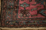 Corner of a vintage Persian rug showing its textured, varied pile and intact dark selvage.