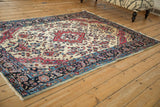 Side angle of an antique Mohajeran Sarouk rug highlighting its ivory field and traditional floral patterns.