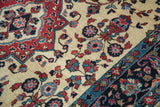 Palmette border detail against the floral ivory field of an antique hand-knotted Sarouk rug.