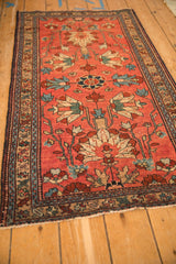 An angled view along the raspberry red field of an antique Mehreban rug with geometric palmettes.