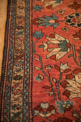 Geometric border and large-scale floral palmettes on the raspberry red pile of an antique Mehreban rug.