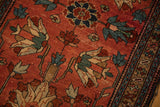 Geometric floral palmettes in dusty teal and ivory on a raspberry red hand-knotted pile.