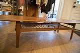 Side profile of the Mid-Century Modern sled coffee table's teak frame and woven shelf.