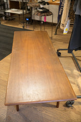 High-angle view of the teak coffee table's top, showing its linear grain and patina.