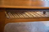 Angled detail of the woven cane shelf within the teak frame of the coffee table.