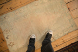 Person's view of a distressed Turkish Oushak rug showing its texture and soft seafoam green palette.