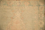 Mostly even wear across the hand-knotted pile of a distressed Oushak in seafoam and dusty rose.