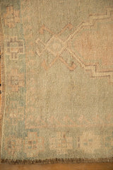 Textured, time-softened pile on the seafoam green and dusty rose border of an Oushak rug.