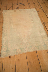 Vintage distressed Oushak rug viewed from an angle, showing the unidirectional stepped prayer design.