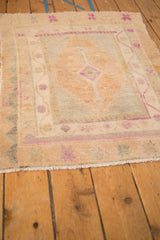 Corner detail of a distressed Turkish Oushak rug with magenta starbursts and a low, worn pile.