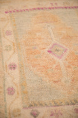 Texture of a distressed Oushak rug showing worn knot heads in dusty gold, silver, and magenta.
