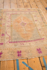 Corner detail of a distressed Oushak rug showing its hand-knotted low pile and fuchsia border patterns.