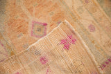 A folded corner shows the hand-knotted foundation and worn pile of a distressed Oushak rug.