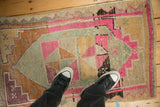 The distressed, low pile texture of a vintage Kars rug with pink and silver pinwheel medallions.