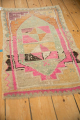 Angled view of a distressed Kars rug with vibrant pink, orange, and silver geometric patterns.