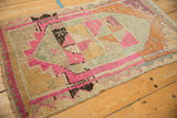 Angled view showing the low pile texture and pink zig-zag border of a distressed Kars rug.