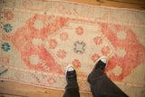 Looking down at the worn texture and soft colors of a distressed vintage Oushak runner.