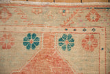 Detail of a vintage Oushak rug's worn pile with teal and pale pomegranate floral motifs.