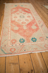 Angled view of a vintage Oushak runner showing its distressed texture and pomegranate red medallion.