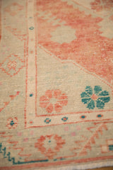 Angled detail of the distressed Oushak rug's weave with teal and pale red floral motifs.