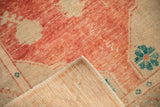 Folded corner of a distressed Oushak rug showing its hand-knotted foundation and secured side cord.