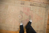 A perspective view showing the even wear and soft, faded palette of a distressed Oushak runner.