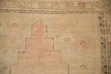 Close-up of a stepped medallion in dusty rose on the heavily abrashed, low pile of a vintage Oushak.