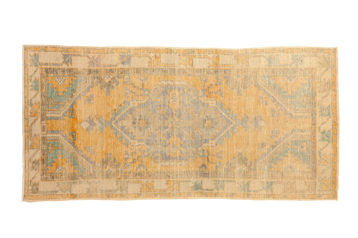 Distressed vintage Oushak rug with a shield medallion in faded saffron yellow and turquoise green.