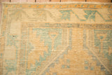 Worn pile of a distressed Oushak rug showing the saffron yellow and turquoise geometric border.