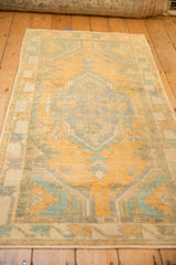 Low perspective view of a vintage Oushak rug in faded saffron, turquoise, and ivory hues.