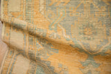 Close-up view of the vintage Oushak's low pile worn to the knot heads and its intact side cord.