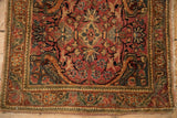 Perched bird with checkered wings in the blush corner spandrel of a vintage Persian rug.