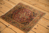 Angled view of a vintage Farahan Sarouk rug showing the bird spandrels and worn edges.