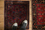 Antique Persian Lilihan mat with floral details in blue and gold on a burgundy field, shown for scale.