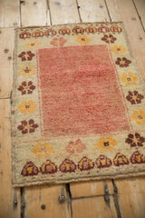 Corner detail of distressed Anatolian rug with floral motifs, cream border, and patinaed red pile.