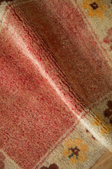 Distressed Anatolian rug pile revealing deep madder red and ivory floral detail.