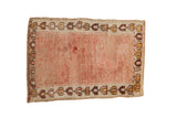 Vintage distressed Anatolian rug with an open rose field showing abrashes and a geometric blossom border.