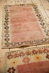 Angled view of a vintage Turkish rug's geometric border and time-softened rose wool pile.