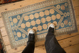 A distressed vintage Oushak rug in sky blue and cream, shown for scale on a wood floor.